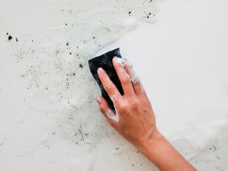 A person scrubbing a white wall with a sponge